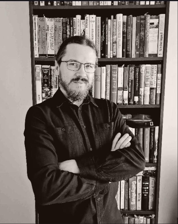 Juliusz Tomczak przy regale z książkami